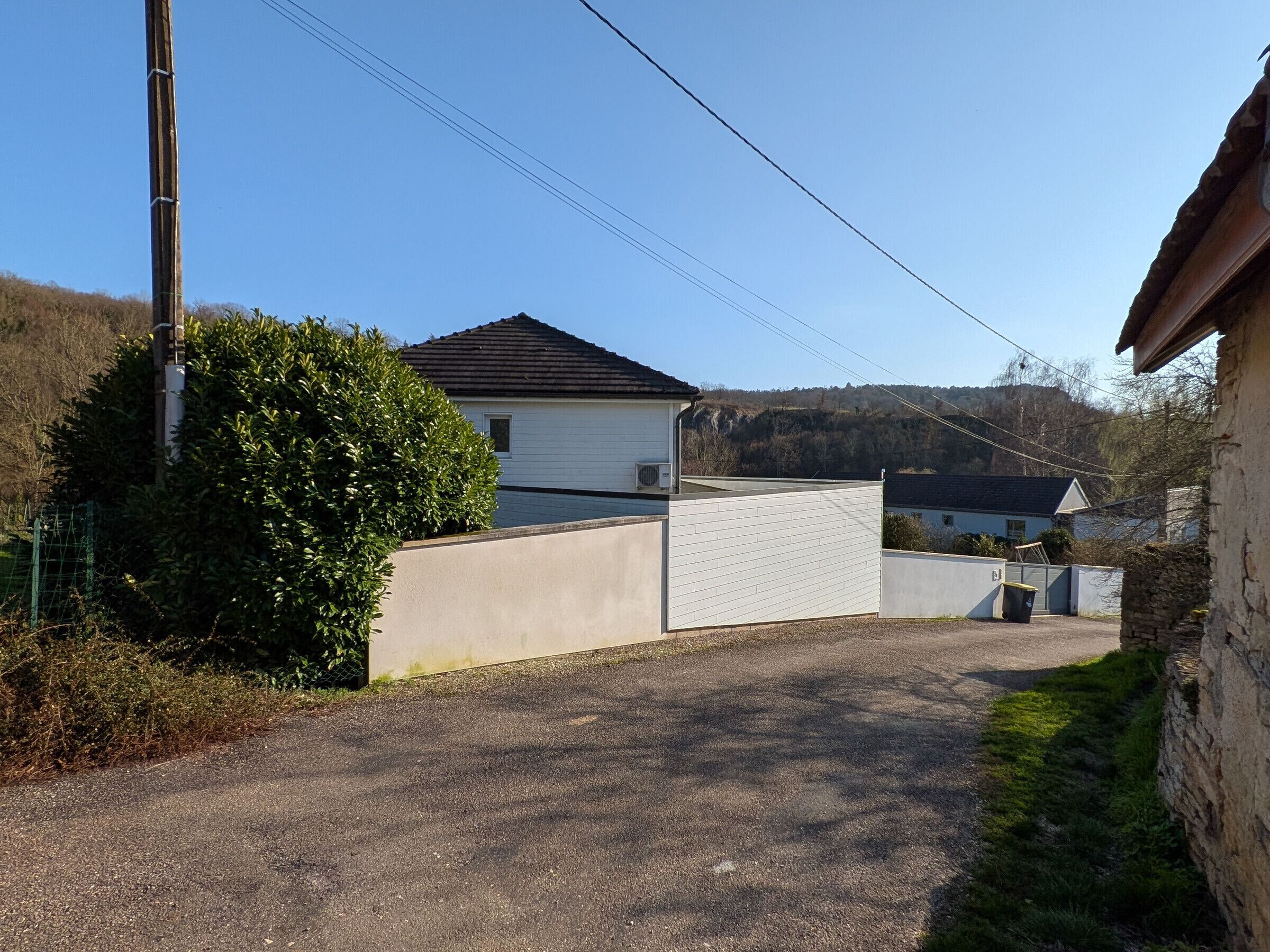 Un barrio residencial con una casa blanca, un camino de grava y un muro de piedra.