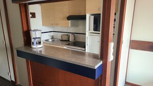 Cocina compacta con refrigerador integrado, cafetera y tostadora.