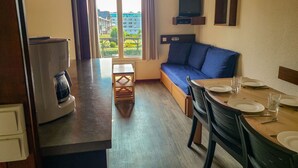 Una habitación acogedora con sofá, una mesita, cafetera y televisor montado en la pared.
