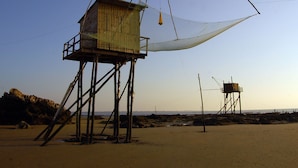 A beach with a wooden structure on stilts, a large white net, and a smaller wooden building in the background. - Quiet cottage near Pornic with wifi, pets welcome (Chauve)