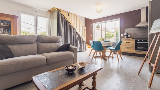 A modern living room with a sofa, a coffee table, and a dining area with chairs and a table. There is a kitchen area with a stove and cabinets. - Quiet cottage near Pornic with wifi, pets welcome (Chauve)