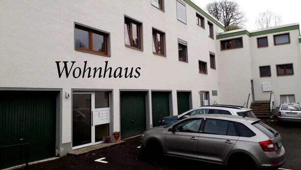 A building labeled "Wohnhaus" with multiple garage doors and parked cars. - Cozy 1-room apartment with large terrace - in the middle of nature (Bad Harzburg)