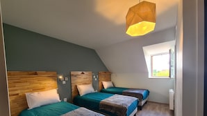 Habitación con dos camas, cada una con cabecero de madera y mesita de noche. Se ve un ventanal con vistas a zonas verdes.