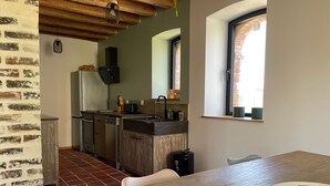 A kitchen with wooden cabinets, a sink, and a window. - Charming cottage near Le Mans with natural pool (Teloché)