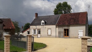 A residential property with a gravel driveway, a gated entrance, and a house with a tiled roof and stone walls. - Independent House with Garden in South Berry (Crozon-sur-Vauvre)