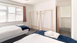 Une chambre d’hôtel avec deux lits, une armoire en bois, un radiateur et une fenêtre avec des rideaux.