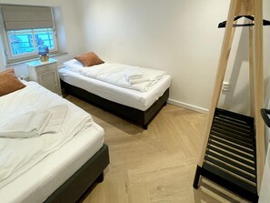 Ein Schlafzimmer mit zwei Betten, einem Nachttisch, einem Fenster mit Jalousien und einer Holzleiter.