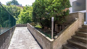 A stone staircase leading up to a building, surrounded by greenery and a metal fence. - Suore Figlie di San Francesco di Sales (La Spezia)