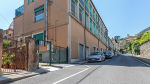 A narrow street lined with parked cars and buildings with balconies. - Suore Figlie di San Francesco di Sales (La Spezia)