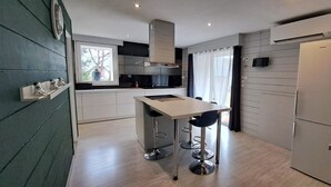 A modern kitchen with a central island, bar stools, and a built-in oven. - Mountain house in 24,000m² park. Pets allowed. (Aucun)