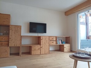 Une pièce avec un meuble en bois, un téléviseur et une fenêtre donnant sur un beau paysage.