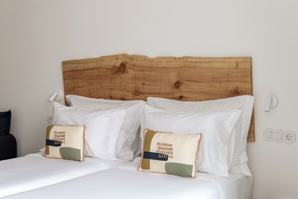 A neatly made bed with white linens and two decorative pillows. - Estúdios Loreto (Fuseta)