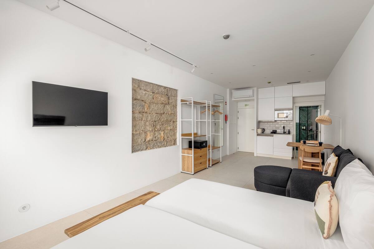 Ein modernes Wohnzimmer mit großem Flachbildfernseher, einer Wand mit Steinakzenten, einer eingebauten Holzausstattung und einem dunkelgrauen Sofa.