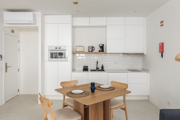 Una cocina moderna con armarios blancos, una mesa de comedor de madera y un horno empotrado.