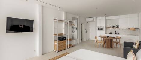 Une chambre à coucher moderne et minimaliste, dotée d’un grand lit, d’une armoire en bois et d’un téléviseur fixé au mur.