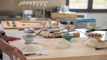 Un piano di lavoro in cucina con farina, un mattarello e un cucchiaio di legno.