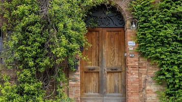 Un edificio in mattoni con una doppia porta in legno, pareti coperte d'edera e un piccolo gradino che conduce all'ingresso.