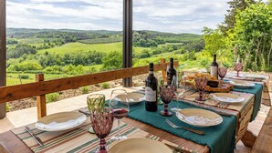 An outdoor dining area with a table set for a meal, overlooking a scenic landscape. - Pociano 1863 (Monteroni d'Arbia)