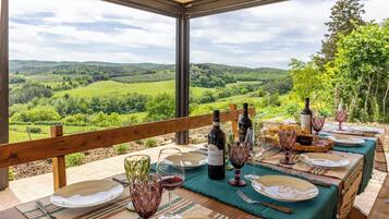 Zona pranzo all'aperto con tavolo apparecchiato per un pasto, con vista su un panorama suggestivo.