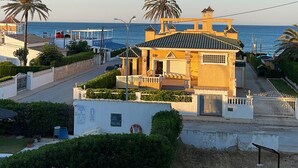 A coastal property with a large house, palm trees, and a view of the sea.