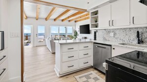 A modern kitchen with white cabinetry, a granite countertop, and a black dishwasher.