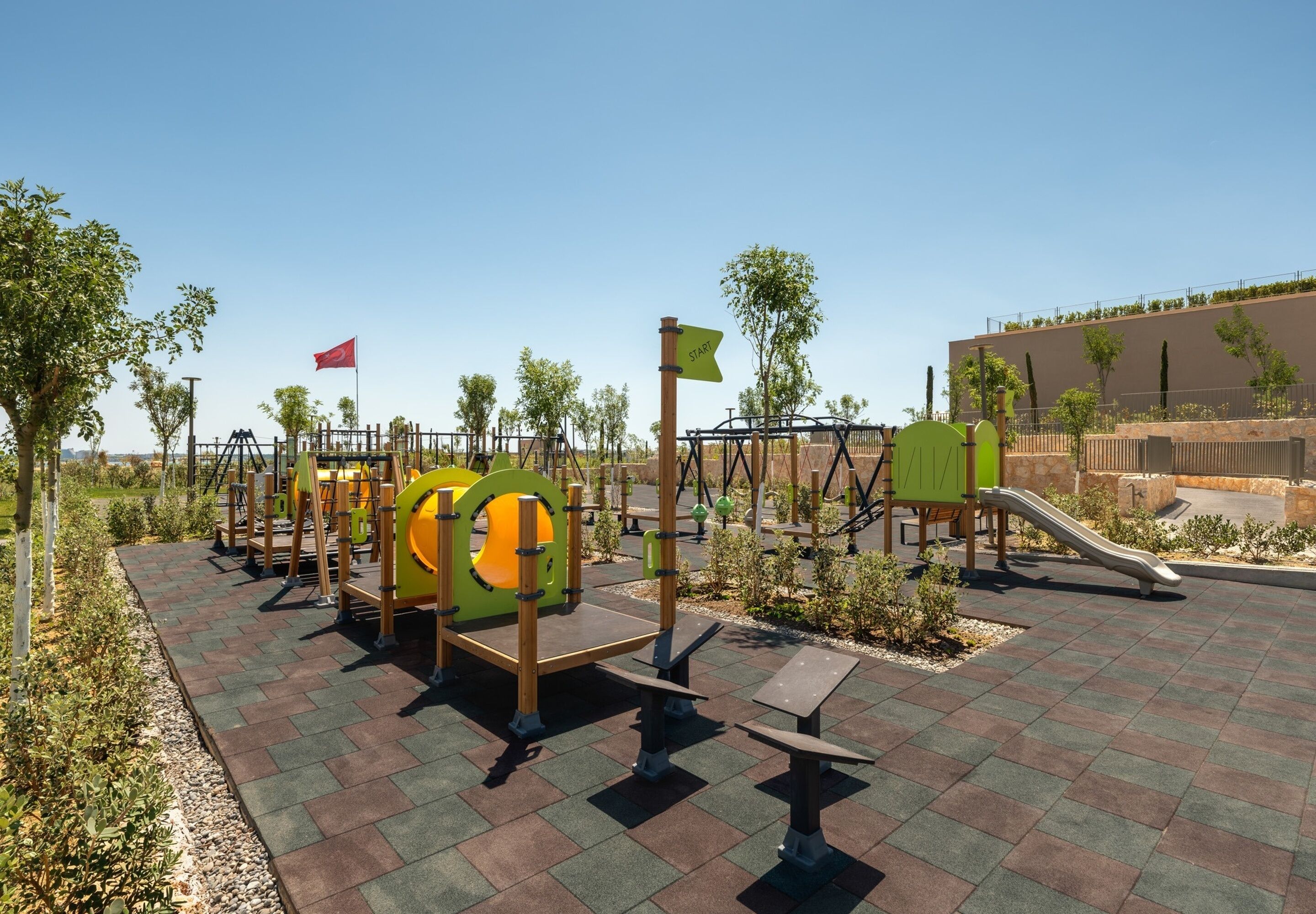 A playground with climbing structures, slides, and a red flag.