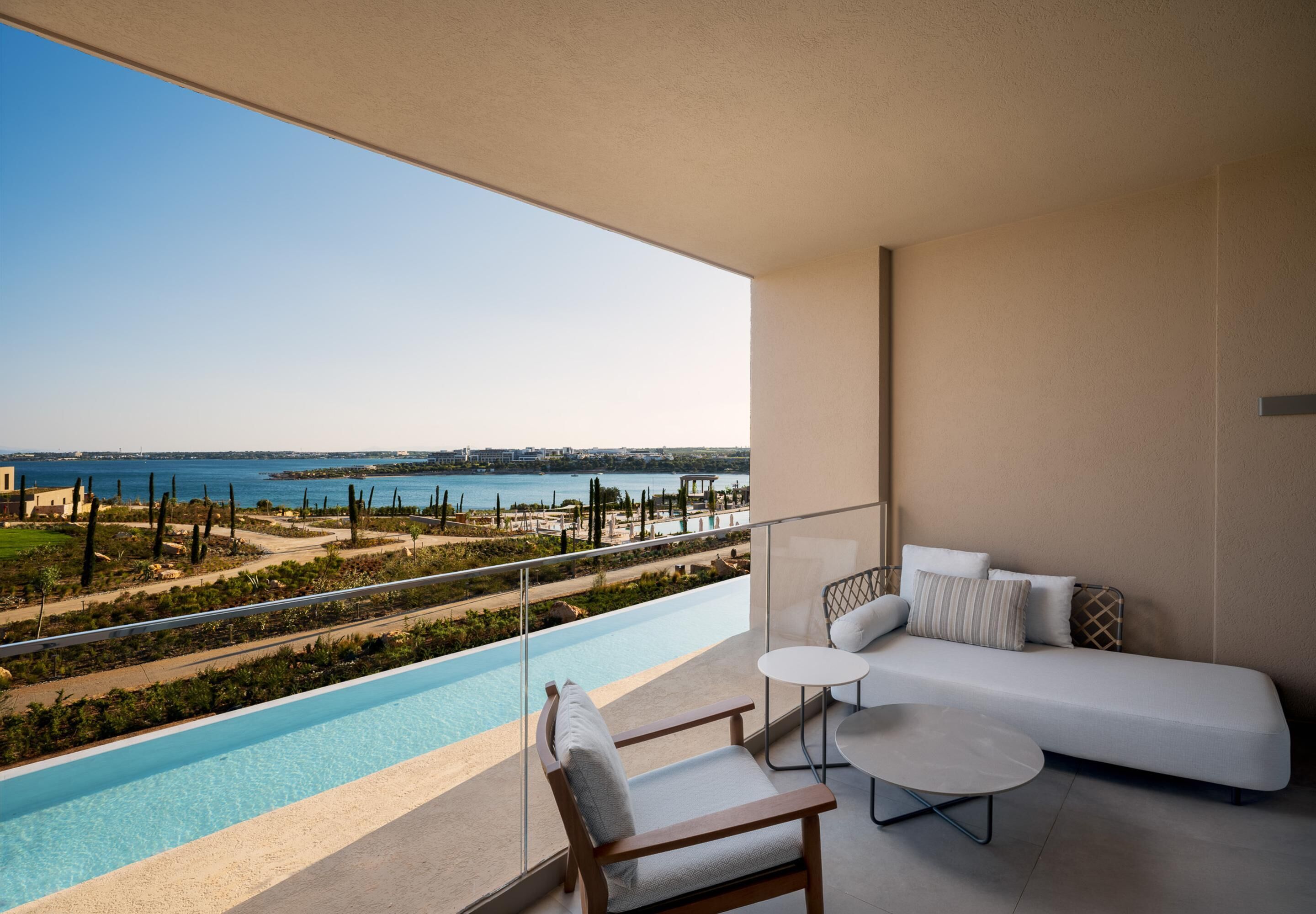 A balcony with a pool, a white sofa, and a small table.