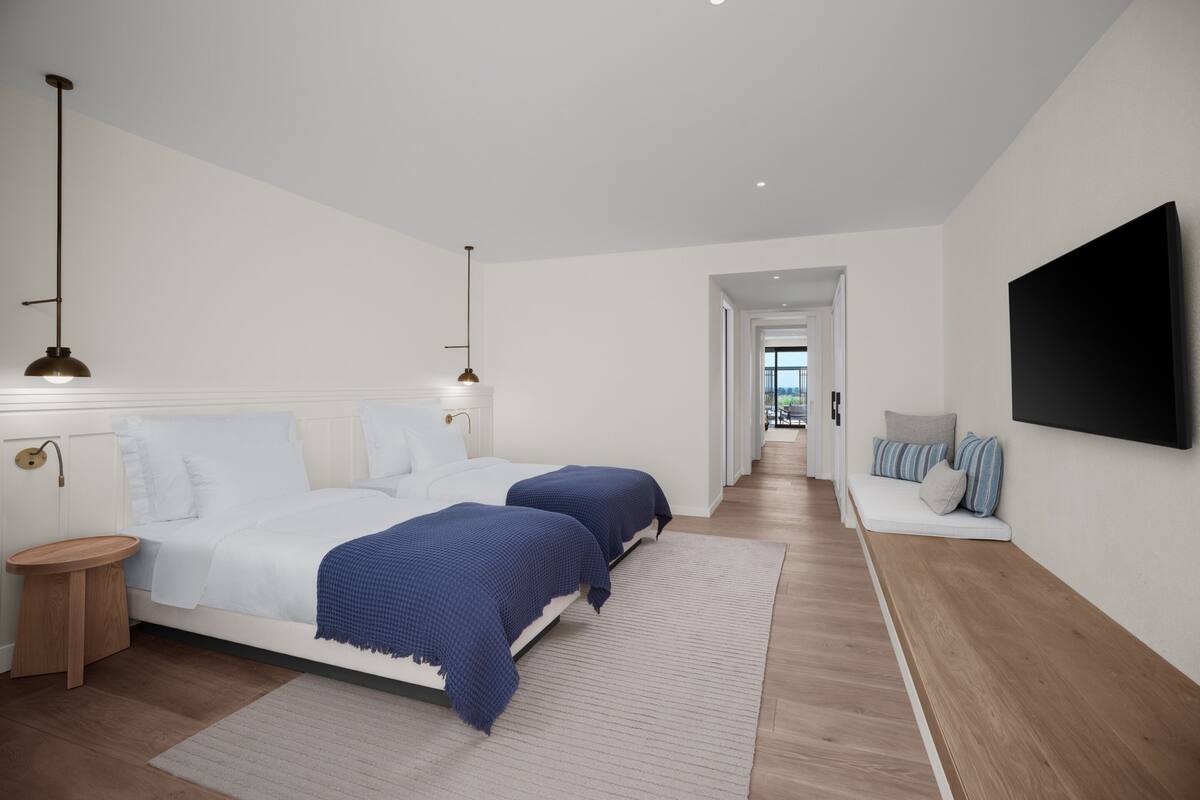 Una camera da letto moderna con un letto grande, comodini, una televisione a schermo piatto e vista all'esterno.