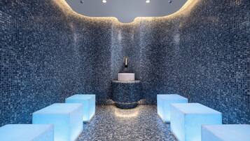 Un baño moderno con paredes de mosaico, un lavamanos central y zonas de estar.