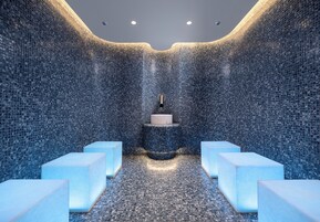 Un baño moderno con paredes de mosaico, un lavamanos central y zonas de estar.
