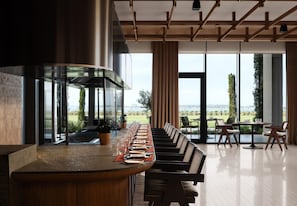 A modern bar area with a long counter, seating, and large windows offering a view. - Akra Didim Resort & SPA (Didim)