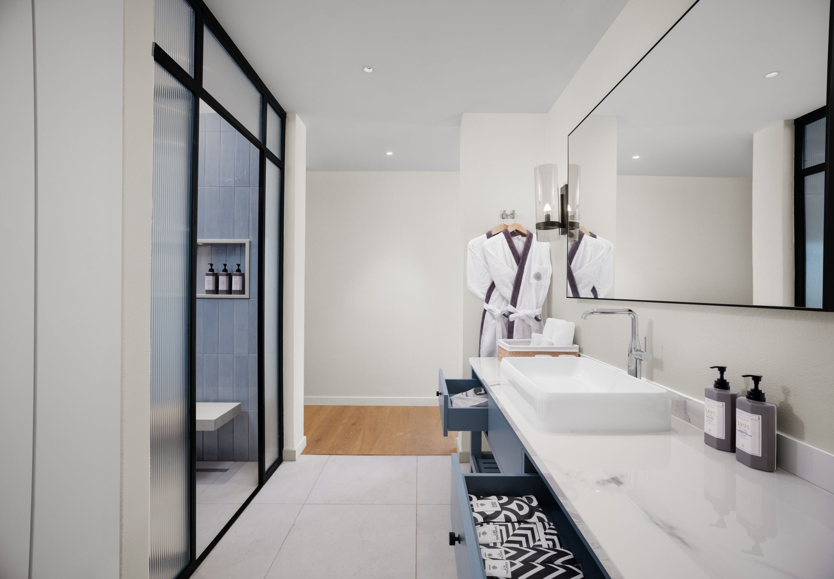 A modern bathroom with a white sink, a mirror, and a towel rack.