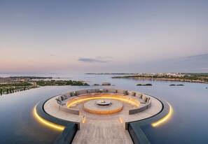 A circular outdoor seating area with a fire pit, surrounded by a low wall and a curved pathway leading to it. - Akra Didim Resort & SPA (Didim)