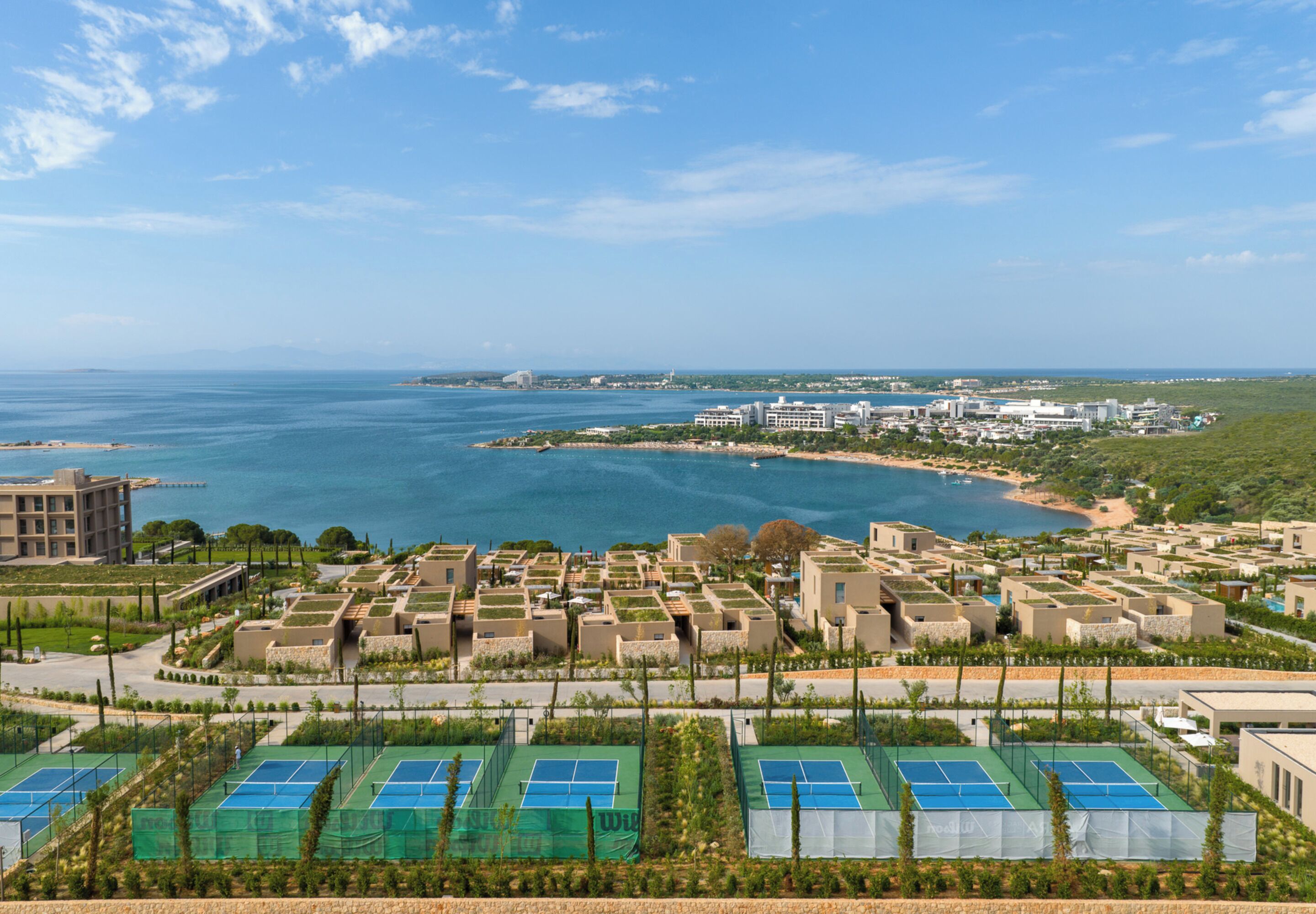 A coastal resort with multiple tennis courts, a marina, and a view of the sea.