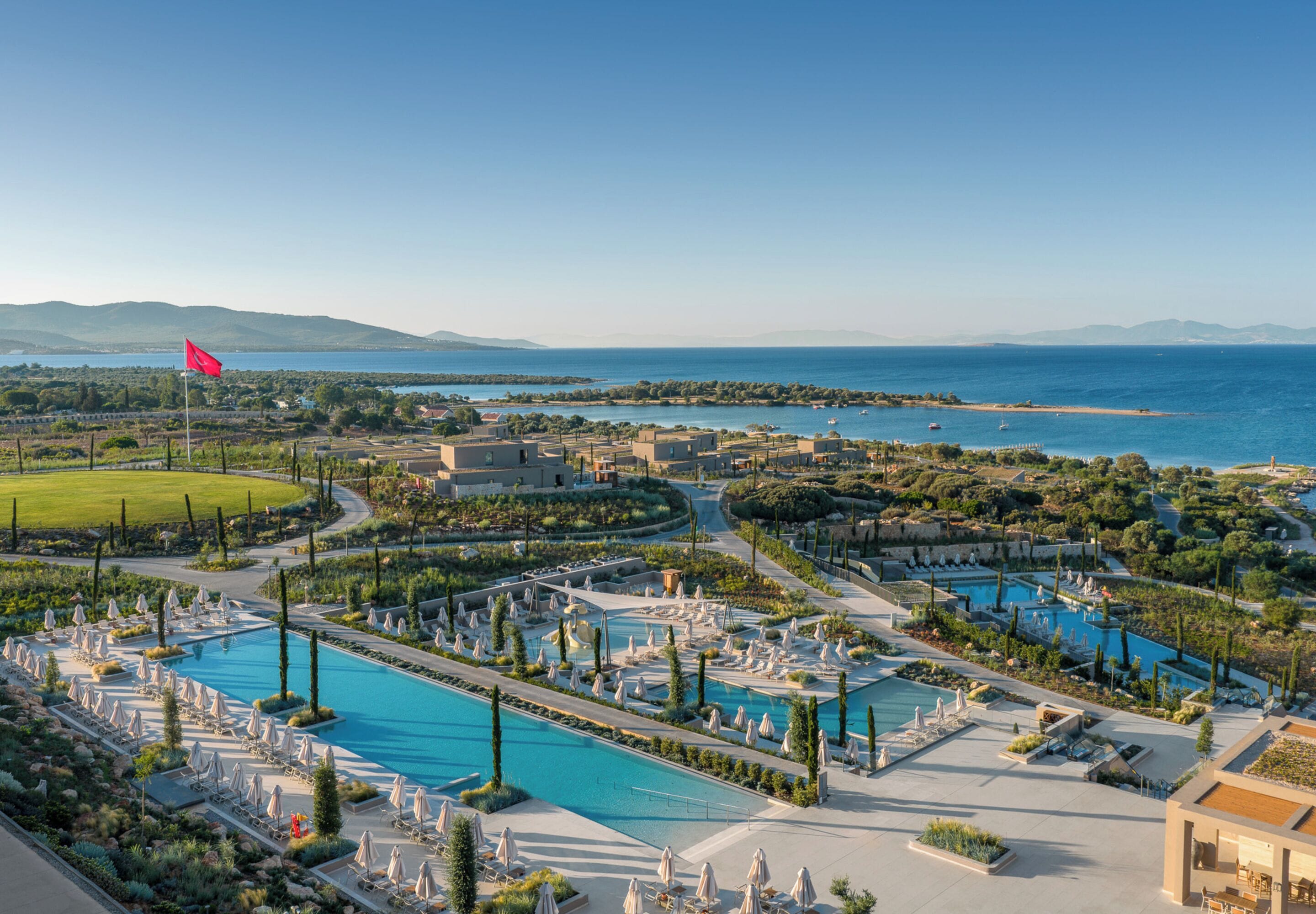 A resort with multiple swimming pools, sun loungers, and a flag.