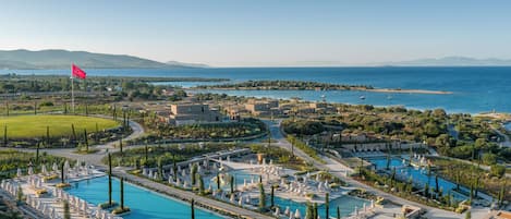 A resort with multiple swimming pools, sun loungers, and a flag.