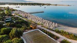 Zona costera con playa, muelle y fila de sombrillas.