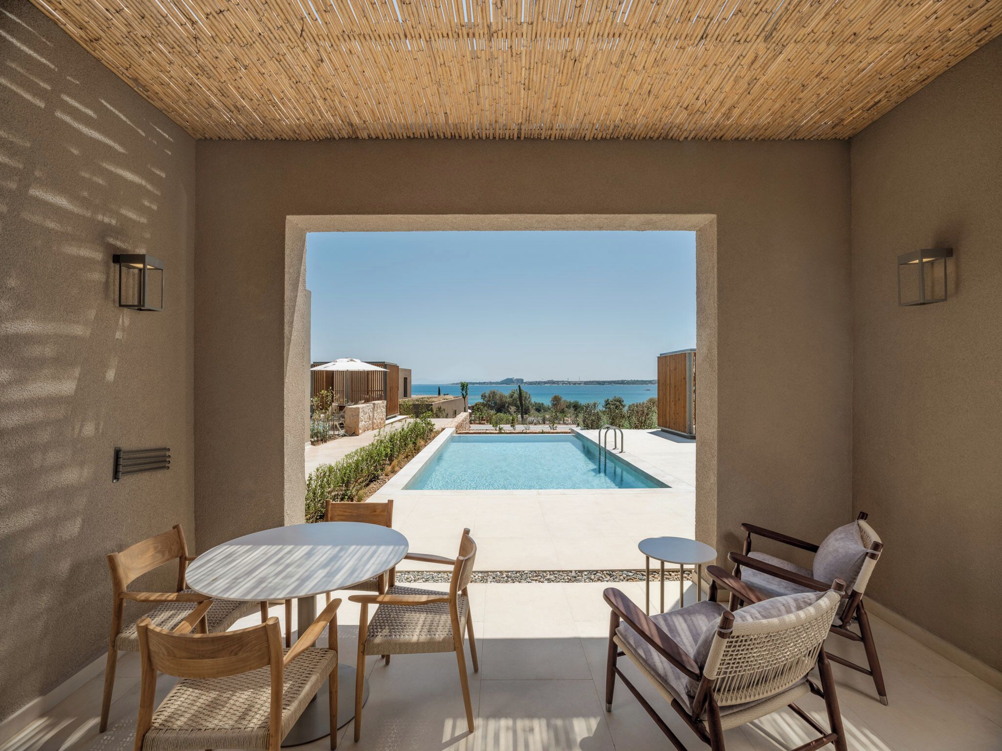Un espace aménagé au bord de la piscine, avec vue sur la mer, comprenant une piscine et du mobilier d’extérieur.