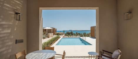 Un espace aménagé au bord de la piscine, avec vue sur la mer, comprenant une piscine et du mobilier d’extérieur.