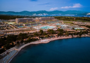 Een resort met meerdere zwembaden, een jachthaven en uitzicht op verre bergen.