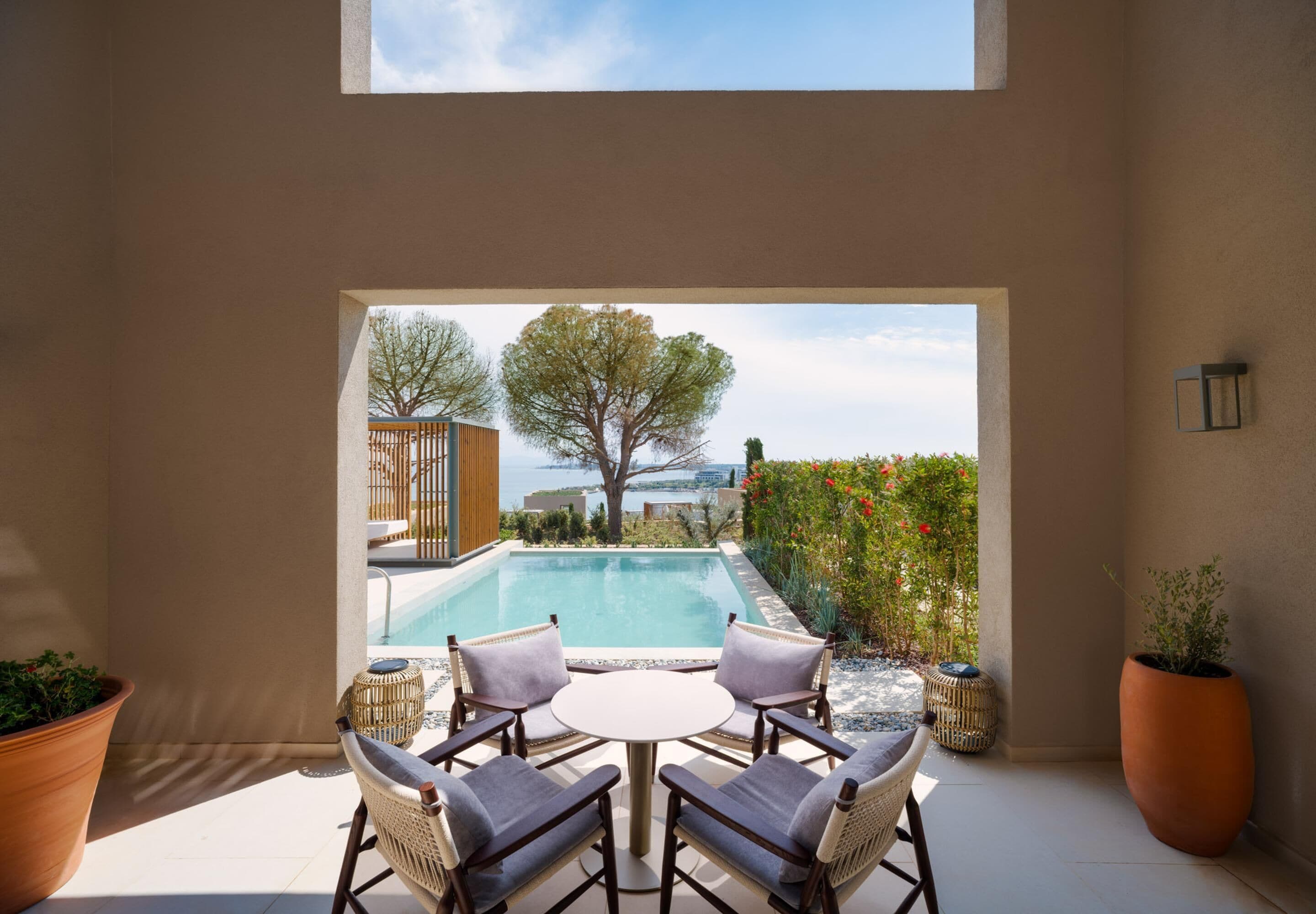 A patio with a pool, outdoor furniture, and potted plants.