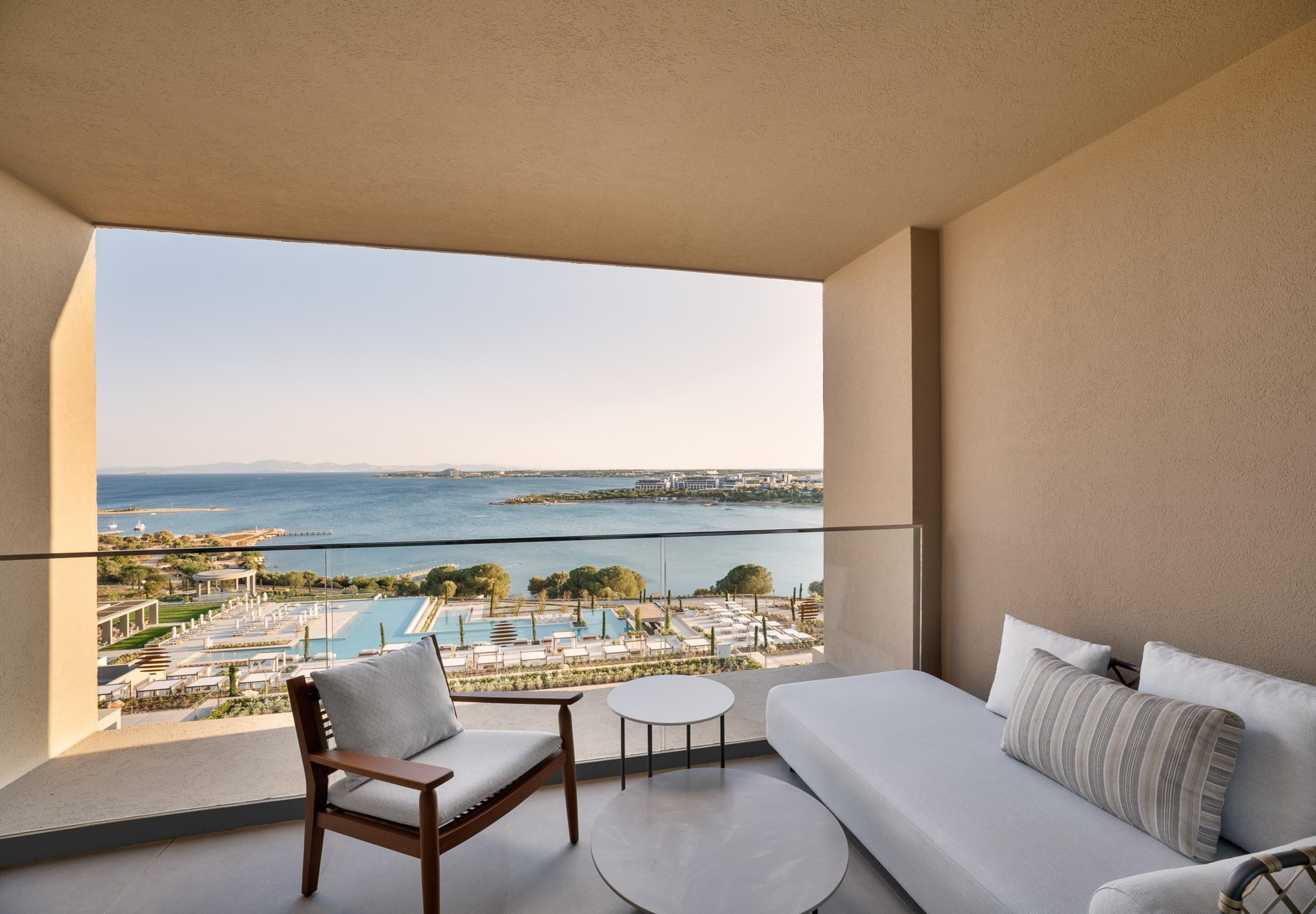 A balcony with a view of a pool and the sea.