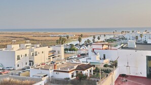 A coastal residential area with modern buildings, a beach in the background, and parked cars. - Conil Beach Studio . (Conil de la Frontera)