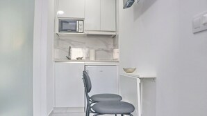 A small kitchenette with a microwave, a sink, and a chair. - Conil Beach Studio . (Conil de la Frontera)