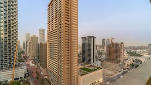 A high-rise building with multiple floors, surrounded by other tall buildings and construction sites. - Modern JVC Studio with Pool Gym and Easy Access to Attractions (Dubai)