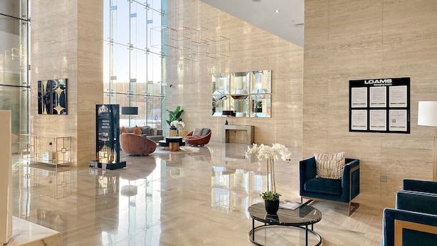 A spacious lobby with a polished floor, seating areas, and large windows allowing natural light. - Modern JVC Studio with Pool Gym and Easy Access to Attractions (Dubai)