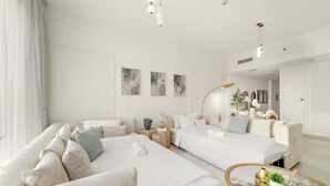 Een moderne, goed verlichte slaapkamer met een groot bed, twee sofa’s, een bijzettafeltje en een ronde salontafel.