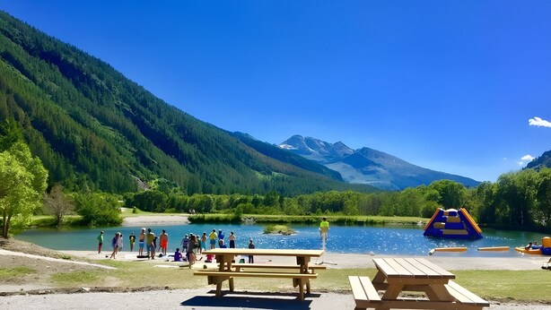 A lakeside park with picnic tables, a playground, and a mountain backdrop. - Apartment "Au refuge d'Hirka" with Mountain View, Balcony, and Wi-Fi (Val-Cenis)