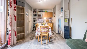 A compact kitchen with a dining table, chairs, and a microwave. - Apartment "Au refuge d'Hirka" with Mountain View, Balcony, and Wi-Fi (Val-Cenis)
