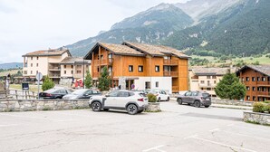 A hotel with multiple floors, a parking lot, and a mountainous backdrop. - Apartment "Au refuge d'Hirka" with Mountain View, Balcony, and Wi-Fi (Val-Cenis)